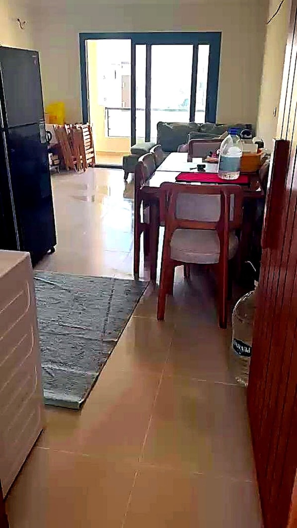 Un coin repas avec une table et des chaises, un réfrigérateur et une vue à travers une porte vitrée.