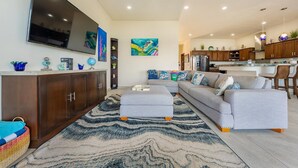 A modern living room with a large flat-screen TV, a sectional sofa, and a patterned rug. - 4BR Oceanfront Home | Incredible Views & Private Pools (Isla Mujeres)