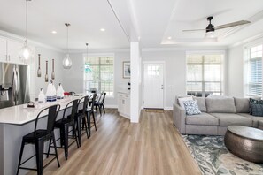 A modern kitchen with a central island, bar stools, and a dining table.
