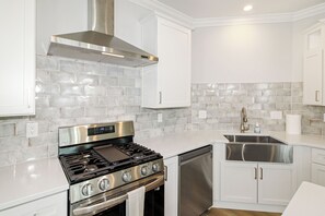 A modern kitchen with white cabinetry, a stainless steel range, and a dishwasher. - Unobstructed Lake Erie Views — Sunrise from the Covered Front Porch (Lakeside Marblehead)