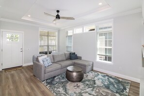 A living room with a sectional sofa, a round coffee table, and a ceiling fan.