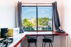 A kitchenette with a microwave, coffee maker, and gas stove. There are two chairs and a window with curtains. - Bright Studio, 2 Mins to Town Centre + Beach (Sayulita)