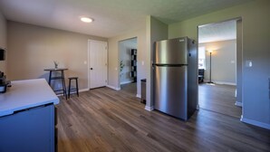 Une cuisine moderne dotée d’un réfrigérateur en acier inoxydable, d’un plancher en bois et d’un petit coin repas avec des tabourets.