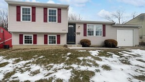 A two-story residential building with a garage, a front door, and a mailbox. - Cozy 2-bedroom house. Office Space. Projector. Coffee Station included. (Cincinnati)