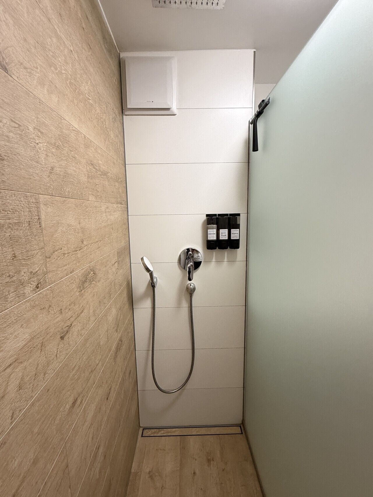 A shower with a handheld showerhead and a wall-mounted faucet.