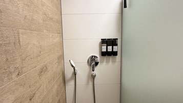 A shower with a handheld showerhead and a wall-mounted faucet.
