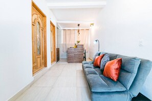 Un salon moderne avec un canapé gris, un meuble en bois et un escalier menant à l’étage supérieur.