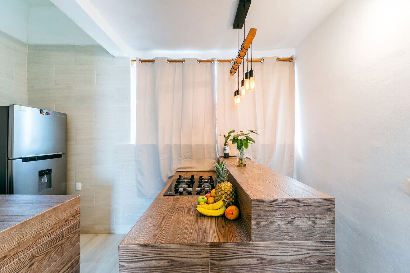 A modern kitchen with a wooden countertop, a stainless steel refrigerator, and a gas stove.
