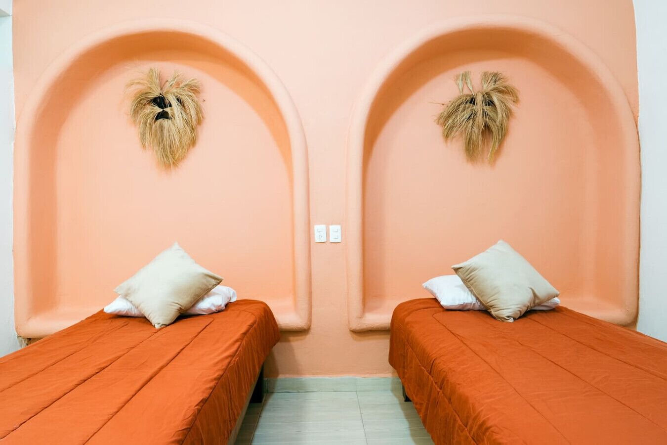 A room with two beds, each with a pillow and a headboard.