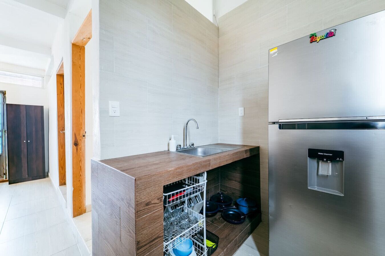 Cocina moderna con refrigerador de acero inoxidable, lavavajillas integrado y encimera de madera.