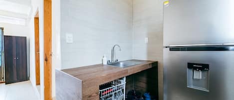 Cocina moderna con refrigerador de acero inoxidable, lavavajillas integrado y encimera de madera.