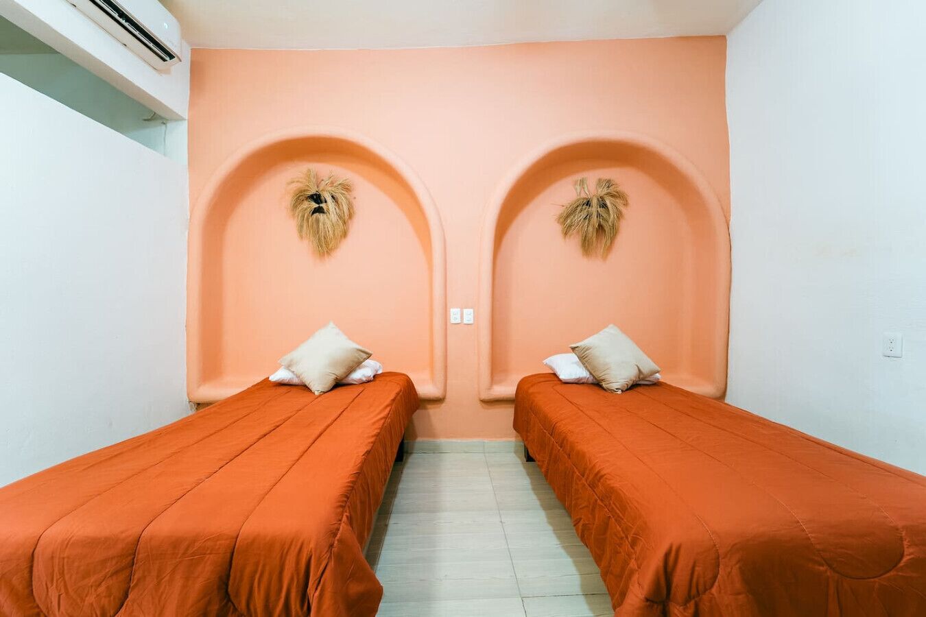 A room with two single beds, each with a pillow and a headboard.
