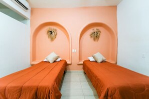 Une chambre avec deux lits simples, chacun étant équipé d’un oreiller et d’une tête de lit.