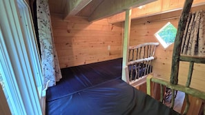 A wooden cabin with a bunk bed, a window with a view, and a wooden staircase. - Waterfront Glamping | La Nomade (Shannon)