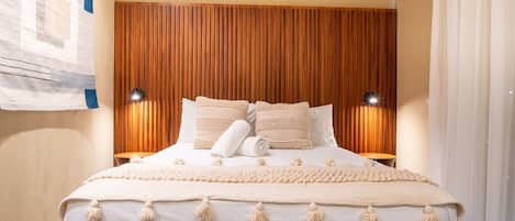 A bed with a wooden headboard, two bedside lamps, and a white bedspread with tassels.