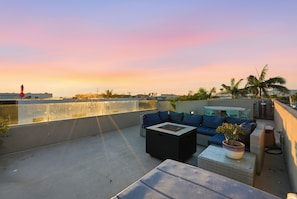 A rooftop terrace with a sofa, a small table, and a potted plant.