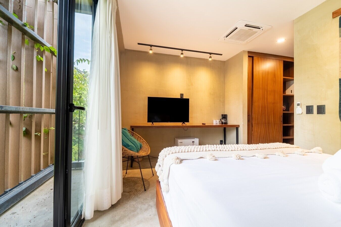 A modern bedroom with a large bed, a television, a desk, and a wardrobe.