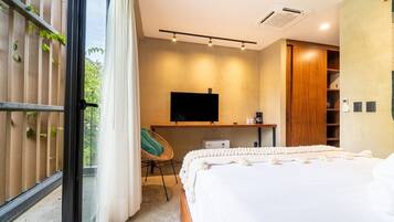A modern bedroom with a large bed, a television, a desk, and a wardrobe.
