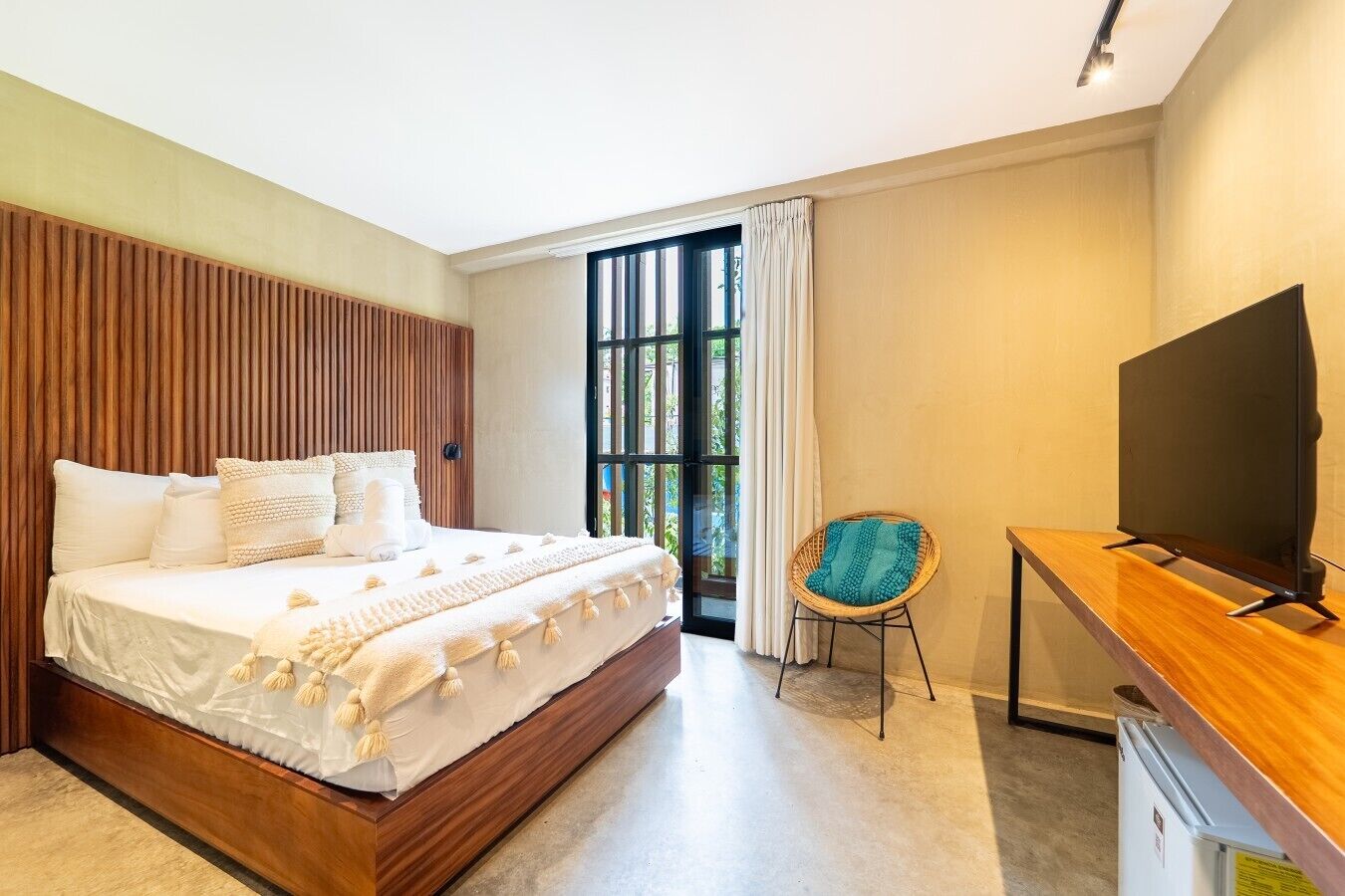 A modern bedroom with a large bed, a television, and a small desk.