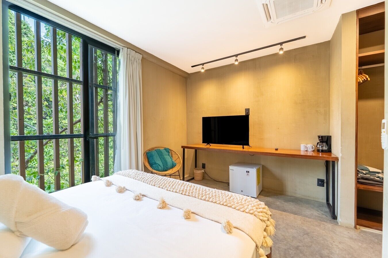 A bedroom with a bed, a desk with a television, a chair, and a wardrobe.