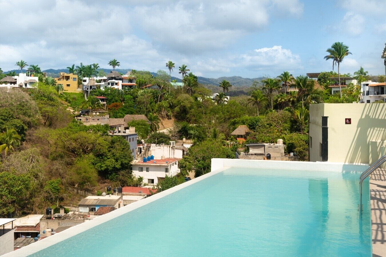 A swimming pool with a view of a residential area and hills in the background.
