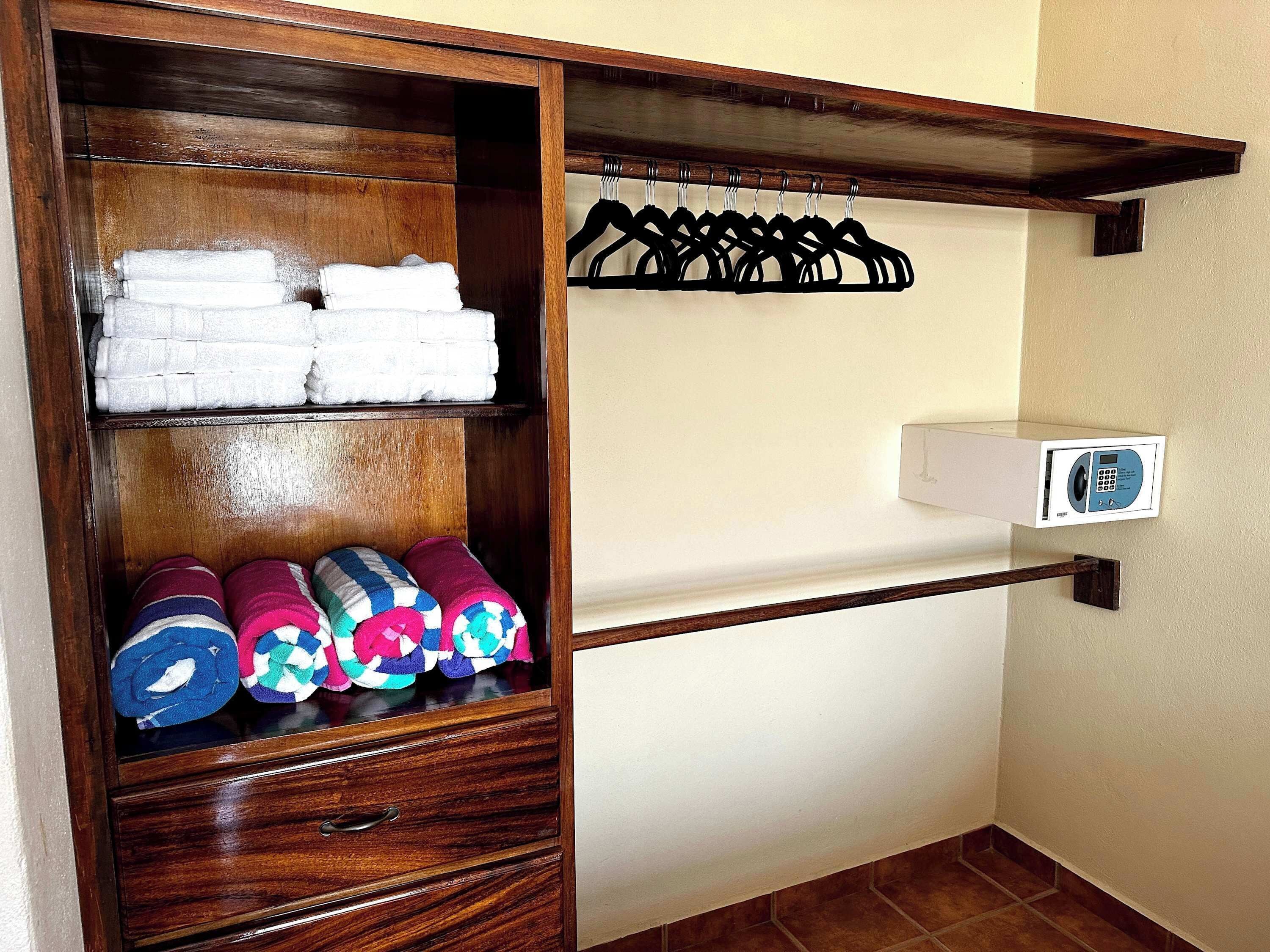 A wooden wardrobe with shelves holding folded towels and rolled-up blankets.