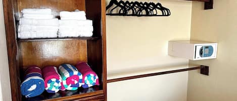 A wooden wardrobe with shelves holding folded towels and rolled-up blankets.