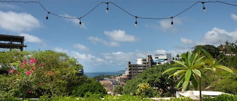 Una terraza con vistas a la ciudad, luces colgantes y abundante vegetación.