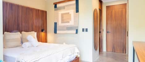 Ein Schlafzimmer mit einem Bett, einem hölzernen Kopfteil, Wandbildern und einer Holztür.