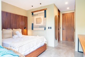 Une chambre à coucher avec un lit, une tête de lit en bois, des œuvres d’art murales et une porte en bois.