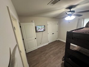 A bedroom with a bunk bed, a ceiling fan, a TV mounted on the wall, and a door leading to another room. - Cozy 2-bedroom 2 full bath townhome in Ruston near Tech Campus! (Ruston)