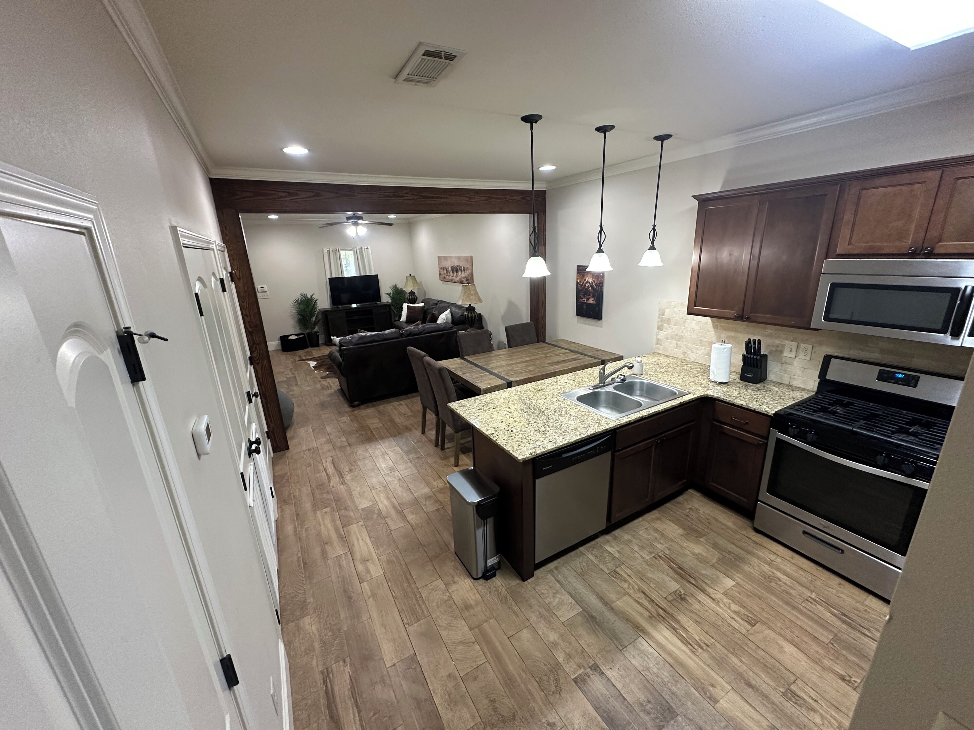 A modern kitchen with granite countertops, stainless steel appliances, and a dining area with a wooden table and chairs.