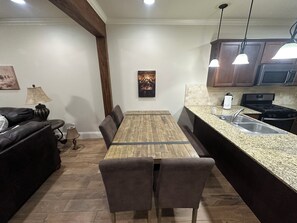 A dining area with a wooden table and chairs, a kitchen with granite countertops and stainless steel appliances, and a dark-colored sofa. - Cozy 2-bedroom 2 full bath townhome in Ruston near Tech Campus! (Ruston)