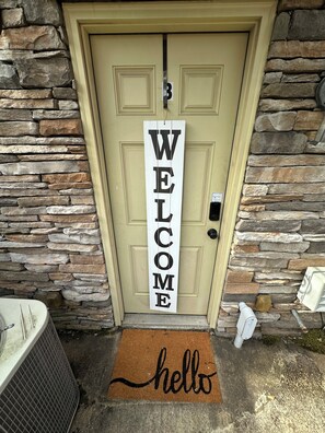 A beige door with a 'WELCOME' sign and a 'hello' mat. - Cozy 2-bedroom 2 full bath townhome in Ruston near Tech Campus! (Ruston)
