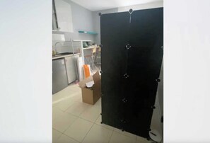 A room with a kitchenette, a desk, and a black partition. - Studio 2P on the Outskirts of Paris (Aubervilliers)