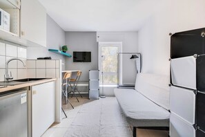 A compact kitchen with a sink, stove, and a flat-screen TV mounted on the wall. - Studio 2P on the Outskirts of Paris (Aubervilliers)