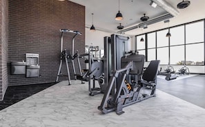 A gym with exercise equipment, a water dispenser, and a large window providing natural light. - Prime Location Rooftop, Pool, Hot Tub & Gym (Salt Lake City)