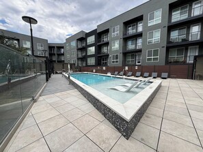 Ein modernes Apartmenthaus mit Schwimmbad, Außenbereich und einem verglasten Balkon.