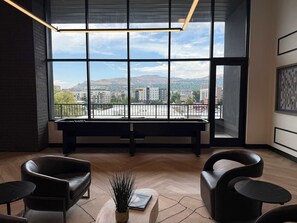 A modern room with large windows, a bench, leather chairs, and a small table with a plant. - Prime Location Rooftop, Pool, Hot Tub & Gym (Salt Lake City)
