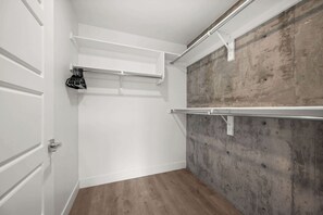 A walk-in closet with white doors, a wooden floor, and a concrete wall. - Prime Location Rooftop, Pool, Hot Tub & Gym (Salt Lake City)