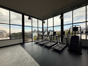 A gym with treadmills and a rowing machine, large windows, and a city view. - Prime Location Rooftop, Pool, Hot Tub & Gym (Salt Lake City)