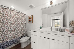 Ein modernes Badezimmer mit Toilette, Waschbecken und Spiegel.