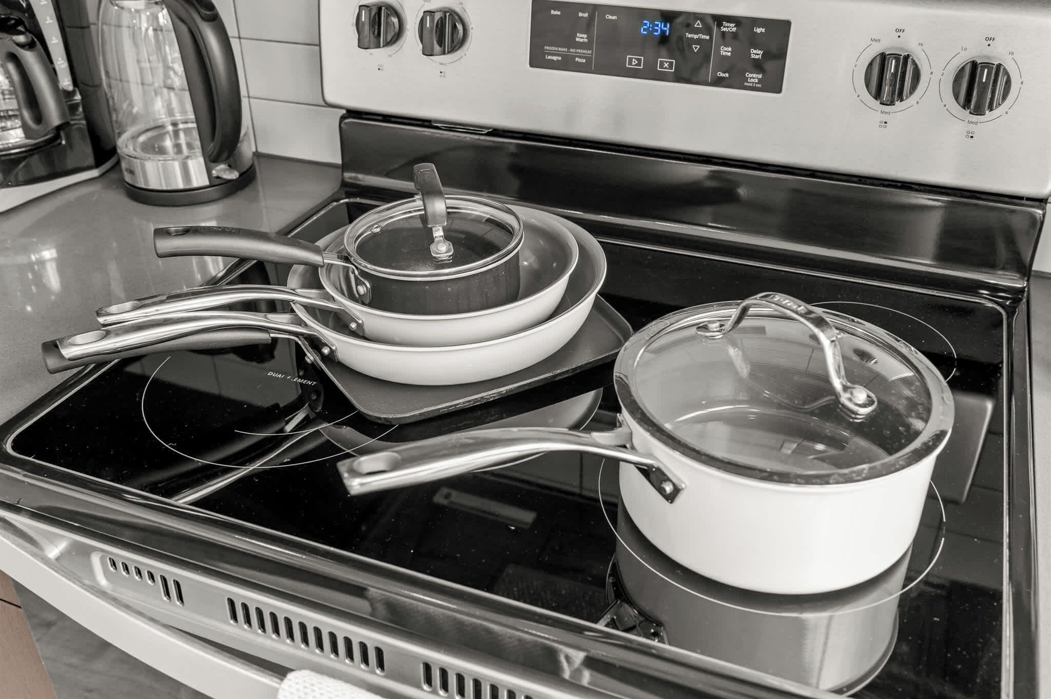 A kitchen with a stove, pots, and a kettle.