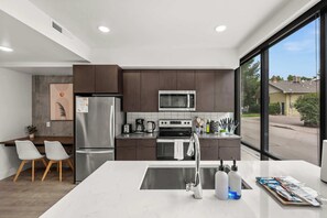 A modern kitchen with a central island, stainless steel appliances, and a view of the neighborhood. - Prime Location Rooftop, Pool, Hot Tub & Gym (Salt Lake City)