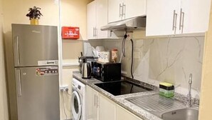 A compact kitchen with a refrigerator, microwave, sink, and a washing machine.