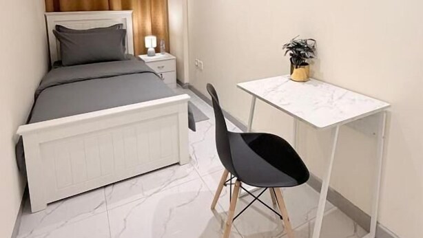 Une chambre à coucher comprenant un lit, une table de chevet, une lampe et un petit bureau avec une chaise.