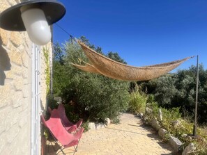 A paved pathway, a red chair, and a hanging shade cloth. - Little House in Provence—The Watering Trough (Flayosc)