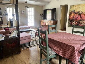 A cozy living room with a television, a dining table with chairs, a bookshelf, and a painting on the wall. - Little House in Provence—The Watering Trough (Flayosc)