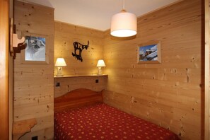 A wooden room with a bed, two wall-mounted lamps, and two framed pictures. - Floor -1, terrace, tv, ski locker, 33m², Aussois (Aussois)
