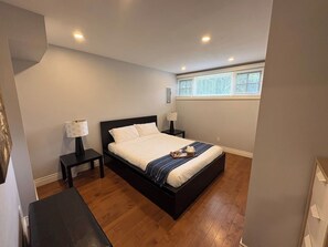 Une chambre à coucher avec un lit, des tables de chevet, une lampe et une fenêtre.